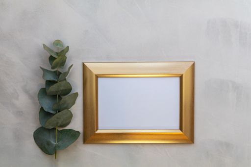 A top view of the golden photo frame with eucalyptus branch