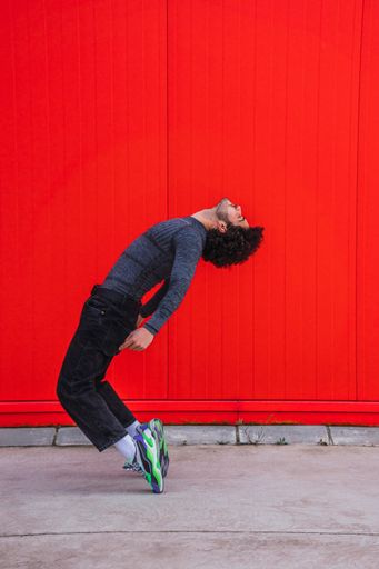 A vertical shot of a Caucasian young athlete posing in front of a red wall