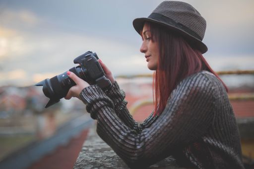 A young Caucasian female from Bosnia and Herzegovina in a shiny blouse holding a camera