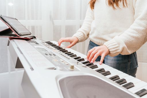 The female using her tablet while playing on a digital piano
