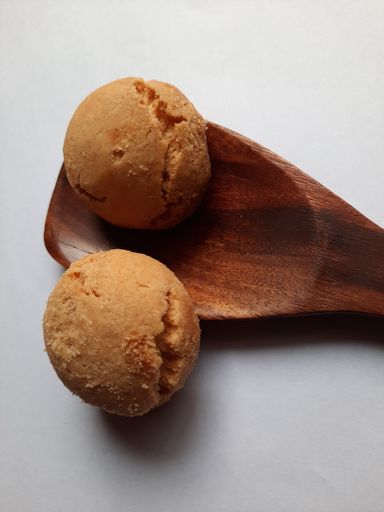 A vertical shot of two freshly baked cookies and a wooden spoon on an isolated background