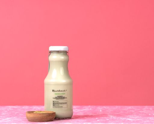 A closeup shot of a vegan milk  in a glass bottle on the pink background