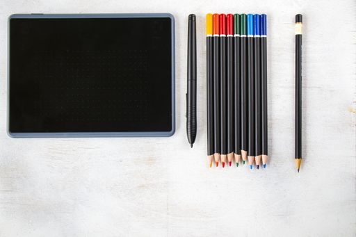 A top view of drawing tablet with pen and pencils on the white background