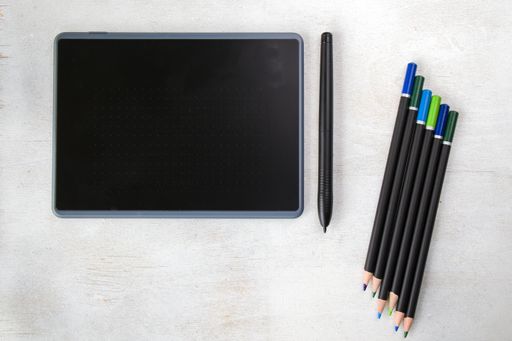A top view of drawing tablet with pen and pencils on the white background
