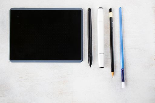 A top view of drawing tablet with pen and pencils on the white background