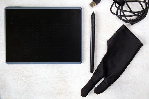 A top view of drawing tablet with pen and glove on the white background