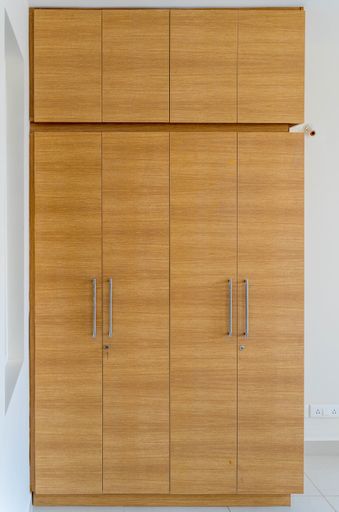 A vertical shot of a wooden wardrobe in the white room