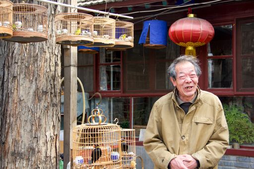 A shallow focus of an elderly man greeting and smiling in his traditional courtyard in China