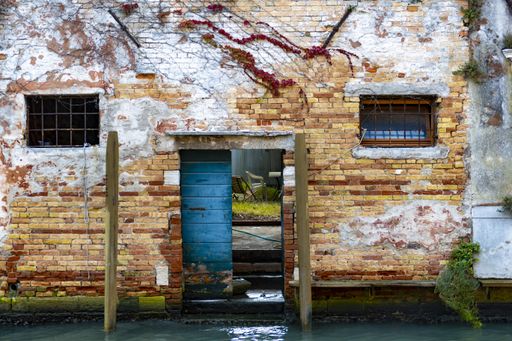 A doorway in the wall of an old brick building by the canal in Venice, Italy