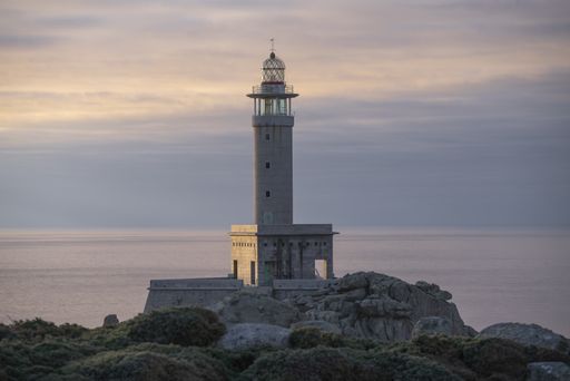 A beautiful view of a Punta Nariga Lighthouse on a coastal cliff during sunrise in Galicia, Spain