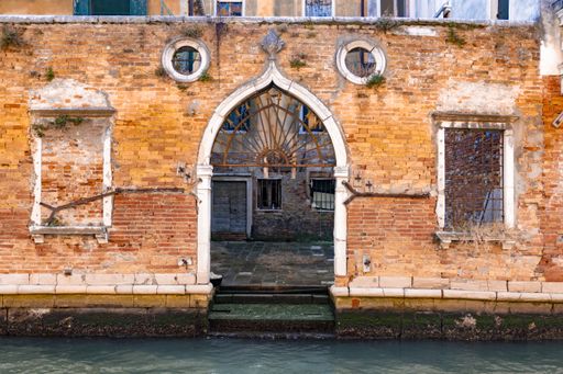 A closeup shot of a building gate with orange small bricks and windows on a sunny day, Veneto, Italy