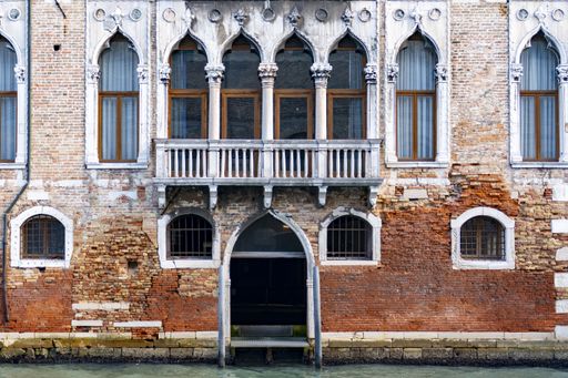 An old orange building with small cracked bricks and beautiful arched window frames in Veneto, Italy