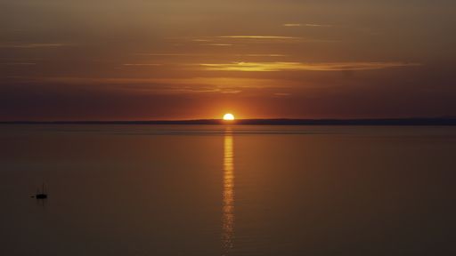 The beautiful orange colors of sunset over the ocean with the silhouette of a fishing boat
