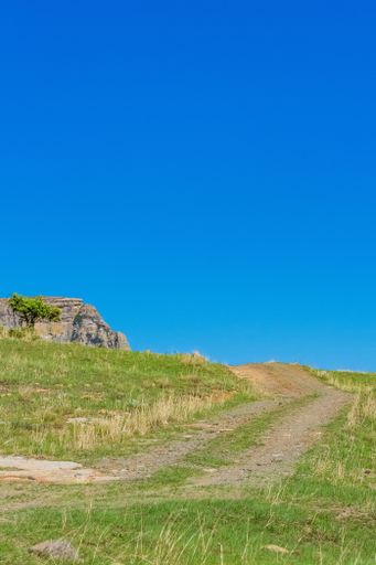 A vertical shot of a path in the hills with the blue sky in the background