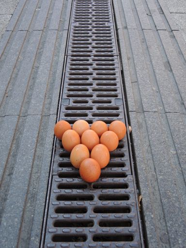 A vertical shot of ten chicken eggs on the street sorted like billiard