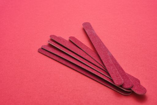 A beautiful shot of red sandpapers made for nail treatment on a light red surface