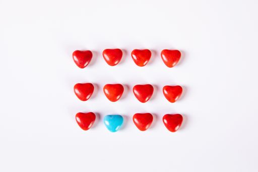 A high angle shot of some red heart-shaped beads and a blue one