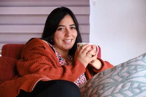 A closeup shot of a Hispanic woman sitting on the couch drinking coffee