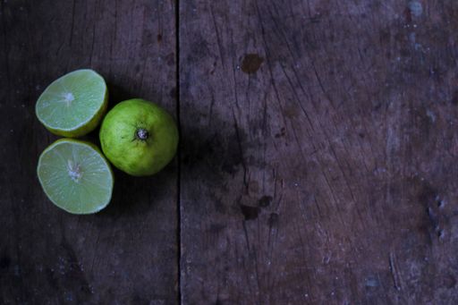 A top view shot of a dark wooden surface with sliced and whole lemons