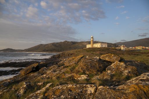 A mesmerizing view of the Larino lighthouse on a hill with foamy ocean waves during a golden hour