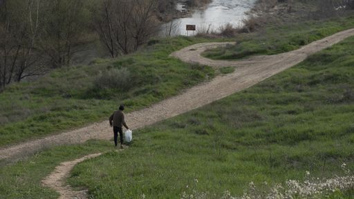 A top view shot of a man walking to the path near to the river