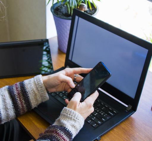 A female working on the laptop and texting on a mobile phone