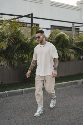 A vertical shot of a tattooed stylish man walking on the street