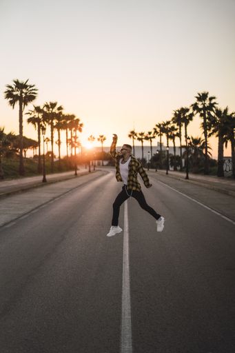 A vertical shot of a young stylish man jumping on the street
