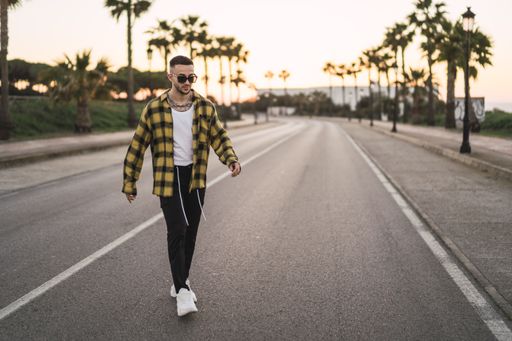 A stylish European man in a plaid shirt walking on a road
