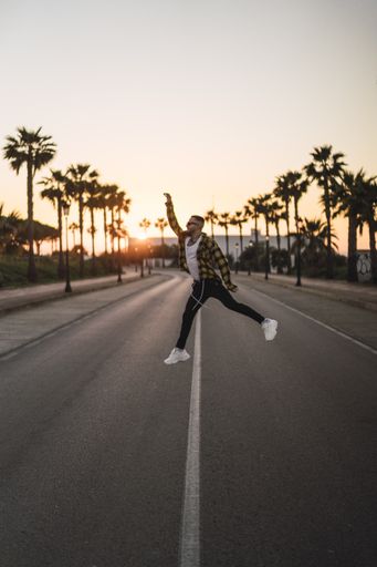 A vertical shot of a young stylish man jumping on the street