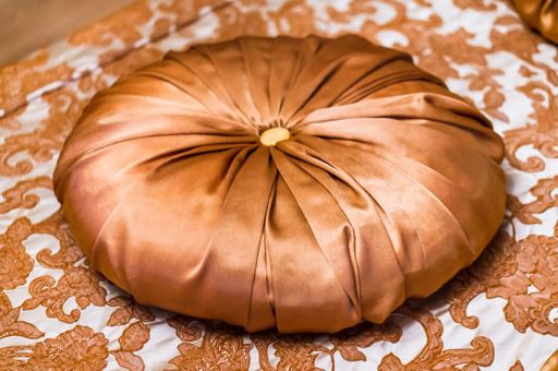A decorative round-shaped cushion on a fabric with floral patterns