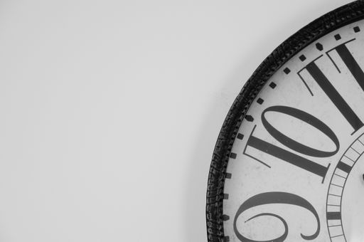 A closeup shot of a clock on the white wall in a room
