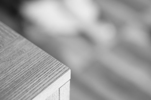 A grey scale shot of the corner of a wooden table in the room