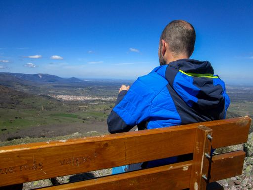 A Spanish man mountaineer sitting on a wooden bench on the top of the mountain