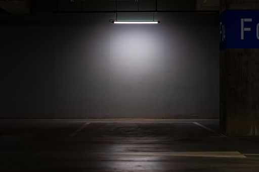 An empty parking lot with an overhead dim light, underground parking garage