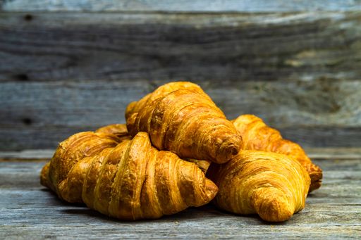 Delicious fresh croissants on wooden table and background - French breakfast