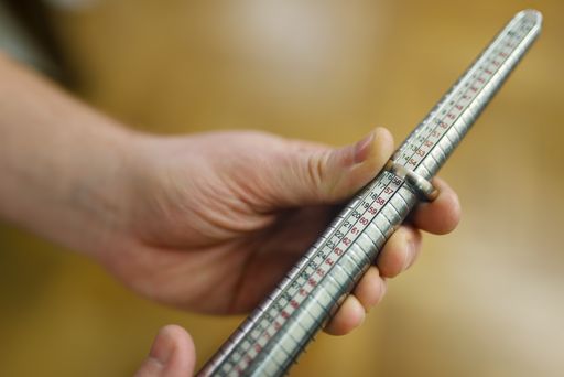 Goldsmith's hand measuring the size of a ring using a ring mandrel.