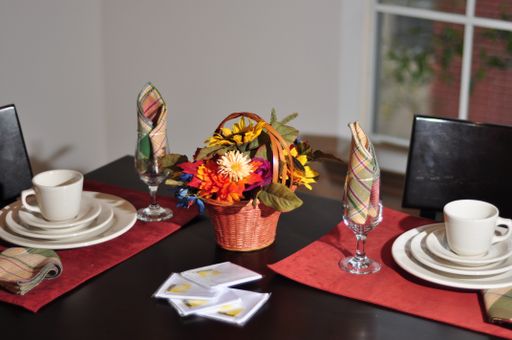 A high angle shot of a table with plates and cups and a flower bouquet