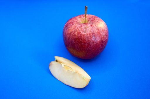 An organic apple with one slice on a blue background