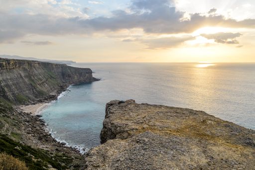 The mesmerizing view of the calm ocean surrounded by rocky mountains during sunset