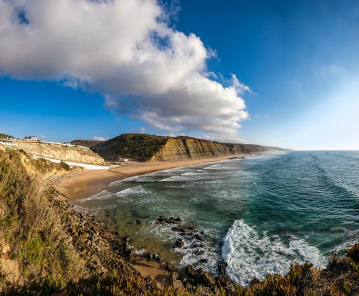 The mesmerizing view of the coastline surrounded by rocky mountains under the blue sky