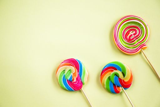 A top view of three colorful lollypops on the light background with a copy space from the left