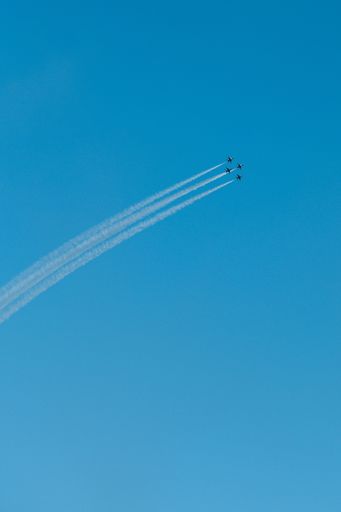 Four aircraft  flying in the sky and doing aerobatic demonstrations with trails of smoke against a blue sky