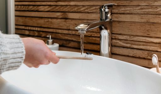 A closeup shot of a hand holding a toothbrush and wash it