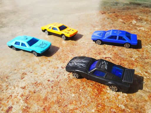 A closeup shot of small toy cars on a brown concrete surface