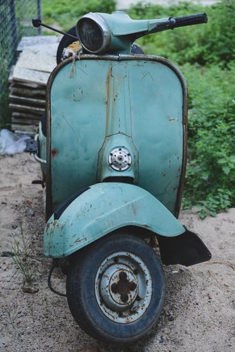 A vertical shot of an old light blue motorcycle parked on the street