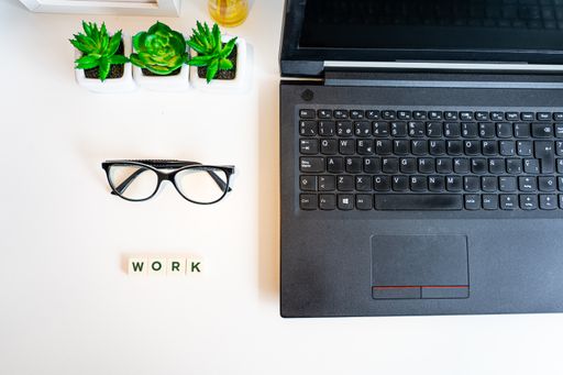 A top view of a laptop and 'work' written on the desk, the new normal