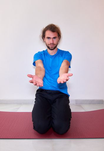 A Spanish young bearded male in sportswear practicing yoga on the yoga mat at home