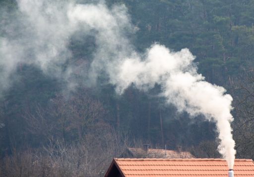 Heavy smoke coming out of a chimney of a building in a forest