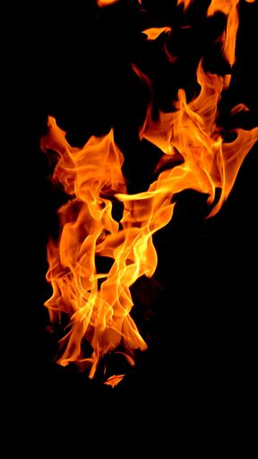 A vertical shot of burning fire on dark background